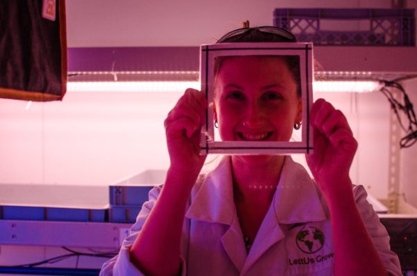 woman smiles while installing vertical farming unit