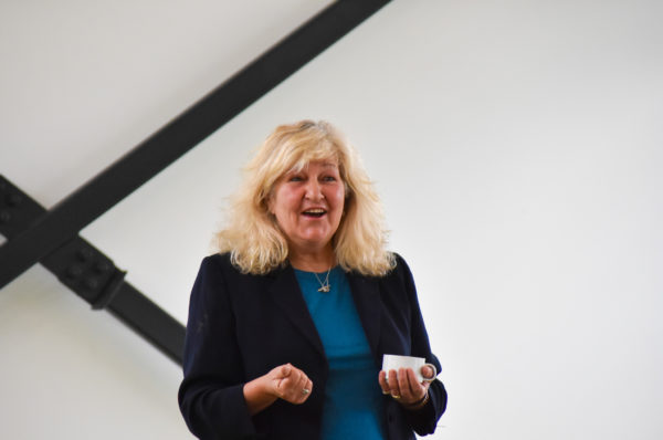 Image of Jenny Phelps holding a coffee cup while holding a Q&A in front of an audience