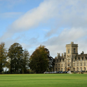 historic building set behind a green field and trees