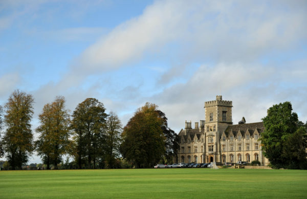 historic building set behind a green field and trees