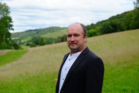 Portrait of a man in the foreground, landscape in the background