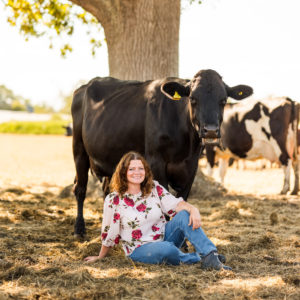 woman seated with a cow standing